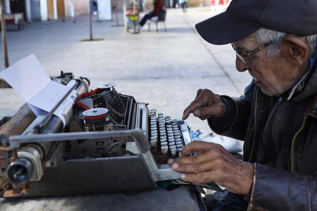 A man offering public typing and writing services uses a traditional typewriter at Bab El Had Square in Rabat, near the entrance to the medina on October 23, 2023. Street typewriting persists in Rabat as public writers provide customers with bureaucratic drafting and formatting of administrative documents. (Photo by Abdel Majid BZIOUAT / AFP)