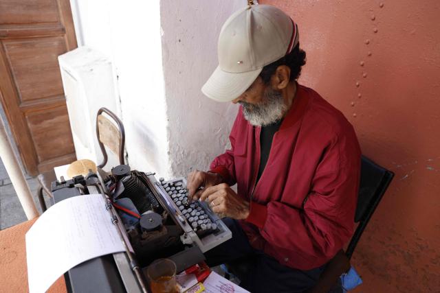 A man offering public typing and writing services uses a traditional typewriter at Bab El Had Square in Rabat, near the entrance to the medina on October 23, 2023. Street typewriting persists in Rabat as public writers provide customers with bureaucratic drafting and formatting of administrative documents. (Photo by Abdel Majid BZIOUAT / AFP)