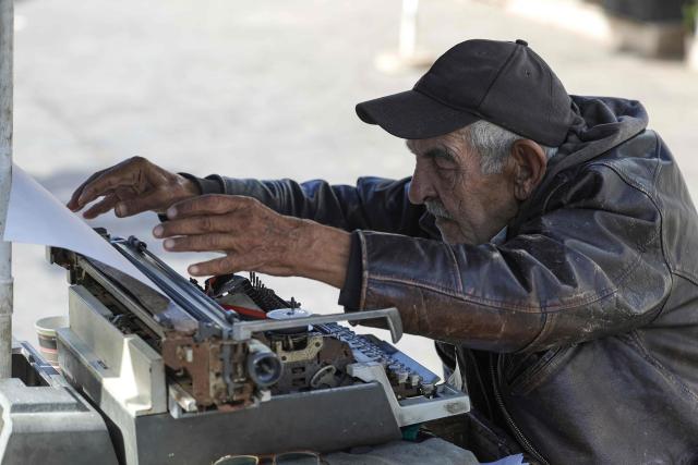 A man offering public typing and writing services uses a traditional typewriter at Bab El Had Square in Rabat, near the entrance to the medina on October 23, 2023. Street typewriting persists in Rabat as public writers provide customers with bureaucratic drafting and formatting of administrative documents. (Photo by Abdel Majid BZIOUAT / AFP)