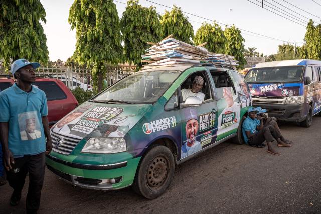 A driver sits inside a vehicle adorned with All Progressives Congress (APC) branding and loaded with campaign posters in Kaduna, on October 23, 2026, ahead of the presidential campaign flag-off rally. Nigerian President Bola Tinubu launches his re-election campaign on Saturday facing voter anger over insecurity and economic hardships. (Photo by Light Oriye Tamunotonye / AFP)