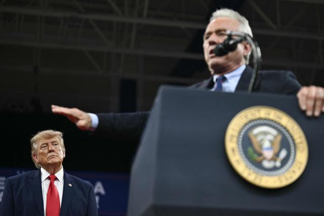US President Donald Trump listens as US Secretary of Health and Human Services Robert F. Kennedy Jr (R) speaks during a campaign rally at the Alico Arena, Florida Gulf Coast University in Fort Myers, Florida on October 23, 2026. (Photo by Brendan SMIALOWSKI / AFP)
