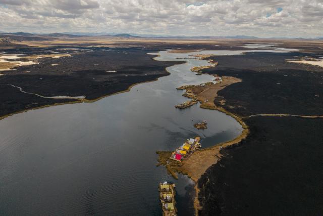 This aerial view shows a huge blackened area in the Lake Titicaca National Reserve near the floating islands of the Uros in Puno, Peru, on October 23, 2026, following a fire that ravaged around 400 hectares of totora reeds on October 21. Forest fires fueled by El Nino have killed 12 people and left hundreds homeless in Peru since June, authorities in the Andean country said on October 21. (Photo by URIEL MONTEFUR / AFP)