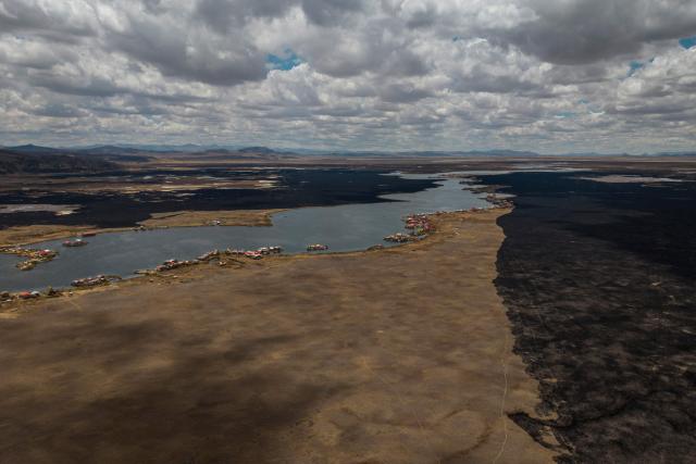 This aerial view shows a huge blackened area in the Lake Titicaca National Reserve near the floating islands of the Uros in Puno, Peru, on October 23, 2026, following a fire that ravaged around 400 hectares of totora reeds on October 21. Forest fires fueled by El Nino have killed 12 people and left hundreds homeless in Peru since June, authorities in the Andean country said on October 21. (Photo by URIEL MONTEFUR / AFP)