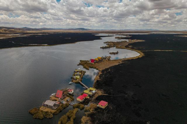 This aerial view shows a huge blackened area in the Lake Titicaca National Reserve near the floating islands of the Uros in Puno, Peru, on October 23, 2026, following a fire that ravaged around 400 hectares of totora reeds on October 21. Forest fires fueled by El Nino have killed 12 people and left hundreds homeless in Peru since June, authorities in the Andean country said on October 21. (Photo by URIEL MONTEFUR / AFP)