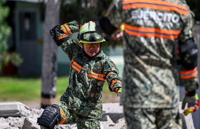 Sergeant Suleyma Tereiro of the Mexican Army takes part in a search-and-rescue exercise amid simulated disaster rubble during a rehearsal marking the 60th anniversary of Plan DN-III-E, Mexico's military emergency response and disaster relief plan, at Santa Lucia Air Base in Zumpango, State of Mexico, Mexico, on October 23, 2026. (Photo by Alfredo ESTRELLA / AFP)