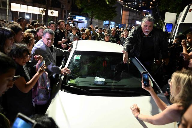 Fans of Argentina's music icon Charly Garcia surround his car outside his residence to celebrate his 75th birthday in Buenos Aires on October 23, 2026. (Photo by Luis ROBAYO / AFP)