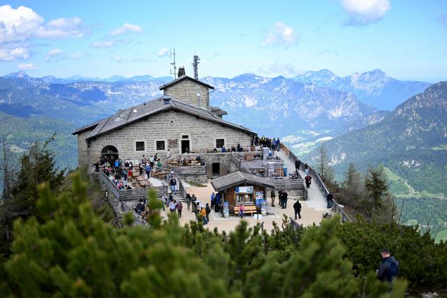 Picture taken on Mai 11, 2025 shows tourists sitting on the terrace of the mountain guesthouse Kehlsteinhaus, that was Adolf Hitler's mountain retreat, known as the Eagle's Nest, seated in the mountains over Berchtesgaden, in the southern German state of Bavaria. Emergency services arrived on site on late October 23, 2026 and found a large fire. German police said on October 24, 2026 they have detained a suspect following a fire at Adolf Hitler's mountain retreat, known as the Eagle's Nest. (Photo by BARBARA GINDL / APA / AFP) / Austria OUT