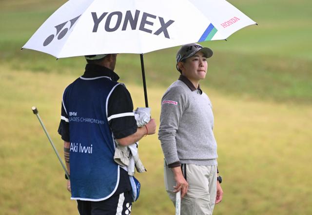 Aki Iwai of Japan stands under her umbrella with her caddie on the 4th green during the third round of the LPGA Tour - BMW Ladies Championship golf tournament at Pine Beach Golf Links in Haenam on October 24, 2026. (Photo by Jung Yeon-je / AFP)