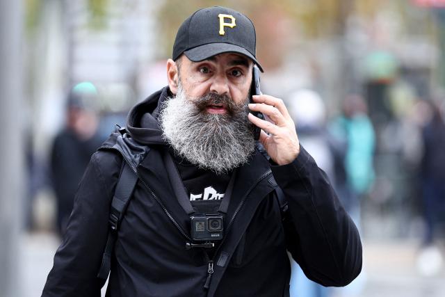 One of the leading figures of the Yellow Vest movement Jerome Rodrigues speaks on the phone as he arrives at Porte d'Italie to attend a demonstration in favor of purchasing power, the protection of public services, and fiscal and social justice, in Paris on October 24, 2026, as part of a nationwide call for mobilisation bringing together former members of the Yellow Vest movement, labor unions, high school and university students. Protests by high school students over learning conditions sparked a movement that has since spread nationwide, fuelled by broader anger over the rising cost of living. About 70,000 security personnel will be deployed on October 24, 2026, Interior Minister said at a news conference, warning that calls for violence and looting were circulating on social media. (Photo by Sameer AL-DOUMY / AFP)