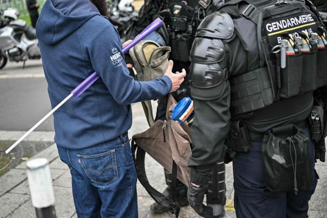 French gendarmes control a protester's bag near Porte d'Italie during a demonstration in favor of purchasing power, the protection of public services, and fiscal and social justice, in Paris on October 24, 2026 as part of a nationwide call for mobilisation bringing together former members of the Yellow Vest movement, labor unions, high school and university students. Protests by high school students over learning conditions sparked a movement that has since spread nationwide, fuelled by broader anger over the rising cost of living. About 70,000 security personnel will be deployed on October 24, 2026, Interior Minister said at a news conference, warning that calls for violence and looting were circulating on social media. (Photo by NICOLAS TUCAT / AFP)