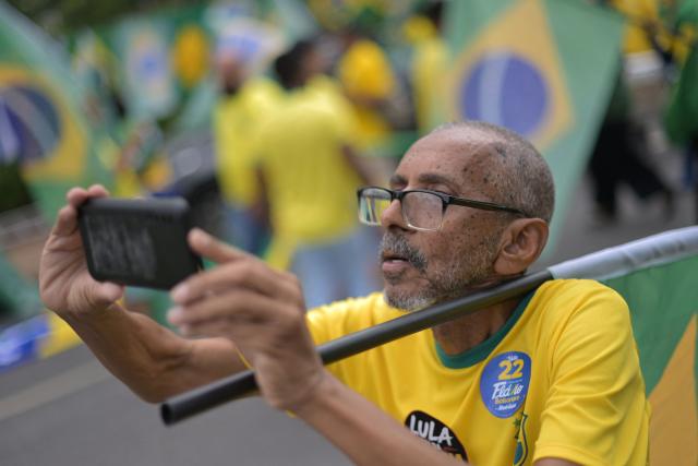 A supporter of Brazil's right-wing Senator and presidential candidate Flavio Bolsonaro of the Liberal Party (PL) records a video with a mobile phone during a campaign rally in Belo Horizonte, Brazil, on October 24, 2026, ahead of the presidential election runoff. (Photo by DOUGLAS MAGNO / AFP)