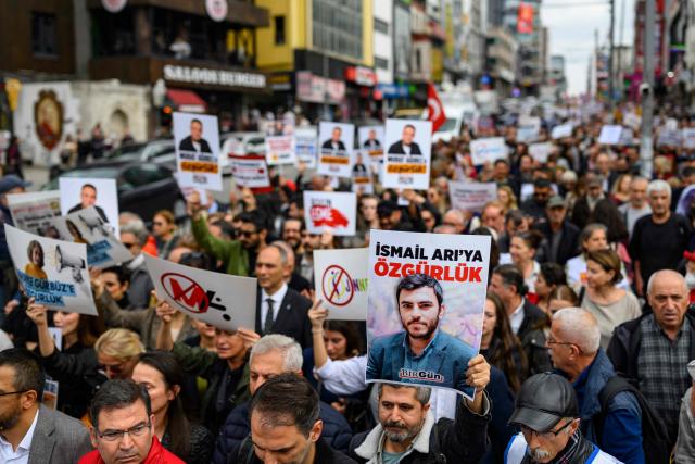 Protesters hold placards, one featirung Ismail Ariya during a rally against what they described as growing pressure on journalists including arrests and media shutdowns, in Istanbul, on October 24, 2026. (Photo by Yasin AKGUL / AFP)