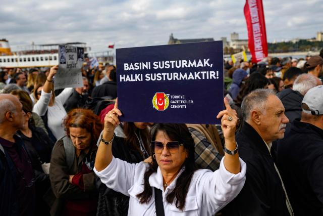 A protester holds a placard reading ''To silence the press is to silence the people'' during a rally against what they described as growing pressure on journalists including arrests and media shutdowns, in Istanbul, on October 24, 2026. (Photo by Yasin AKGUL / AFP)