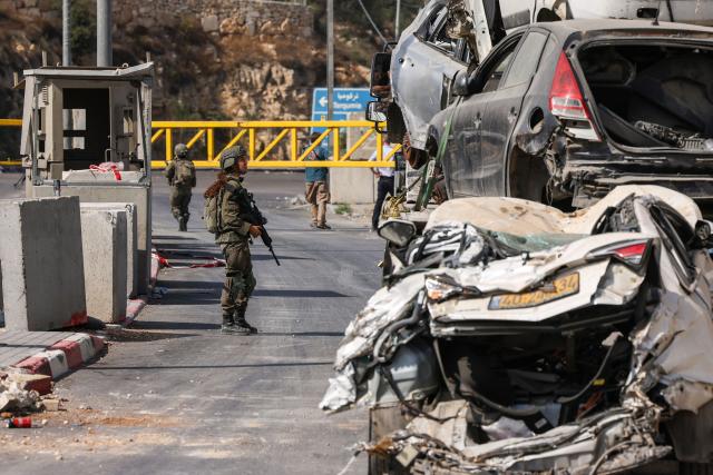 An Israeli soldier speaks with a driver at the blocked northern checkpoint in Hebron, in the occupied West Bank, on October 24, 2026. Israeli forces pushed into the West Bank city of Hebron on October 24 and displaced some 250 families, some in the middle of the night, vowing a heavy price over a deadly attack on soldiers. (Photo by HAZEM BADER / AFP)