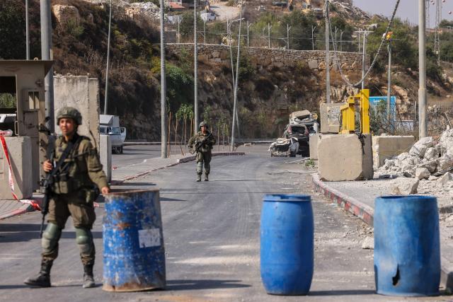 Israeli soldiers stand guard at the blocked northern checkpoint in Hebron, in the occupied West Bank, on October 24, 2026. Israeli forces pushed into the West Bank city of Hebron on October 24 and displaced some 250 families, some in the middle of the night, vowing a heavy price over a deadly attack on soldiers. (Photo by HAZEM BADER / AFP)