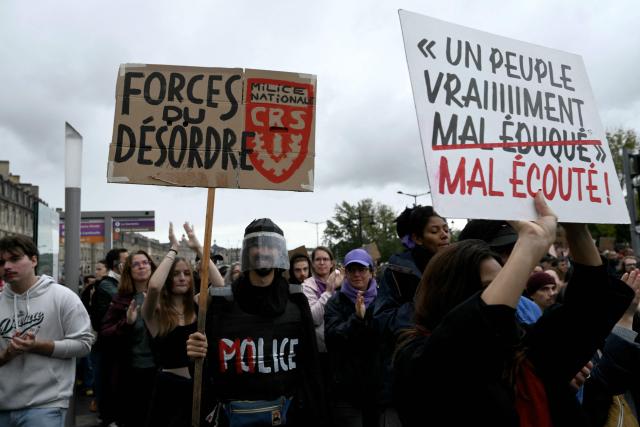 A protester holds a placard reading "Forces of disorder" (a play on words with security forces) during a demonstration in favor of purchasing power, the protection of public services, and fiscal and social justice, in Bordeaux, western France on October 24, 2026 as part of a nationwide call for mobilisation bringing together former members of the Yellow Vest movement, labor unions, high school and university students. Protests by high school students over learning conditions sparked a movement that has since spread nationwide, fuelled by broader anger over the rising cost of living. About 70,000 security personnel will be deployed on October 24, 2026, Interior Minister said at a news conference, warning that calls for violence and looting were circulating on social media. (Photo by Philippe LOPEZ / AFP)