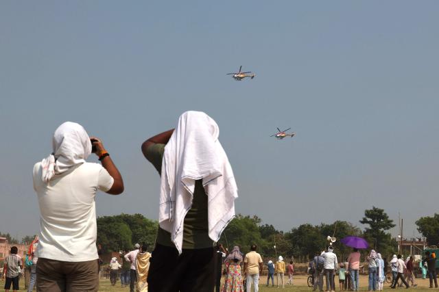 People watch the Indian Air Force (IAF) Sarang helicopters performing during the 'Wings Over Ganges' air show over the river Ganges in Varanasi on October 24, 2026. (Photo by Niharika KULKARNI / AFP)