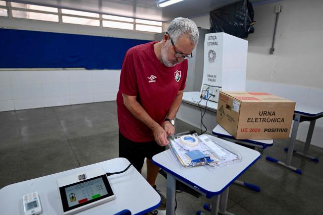 An employee of Brazil's Regional Electoral Court (TRE) sets up a voting booth at a polling station inside a school in Brasilia, on October 24, 2026, on the eve of the presidential election runoff. (Photo by Evaristo Sa / AFP)