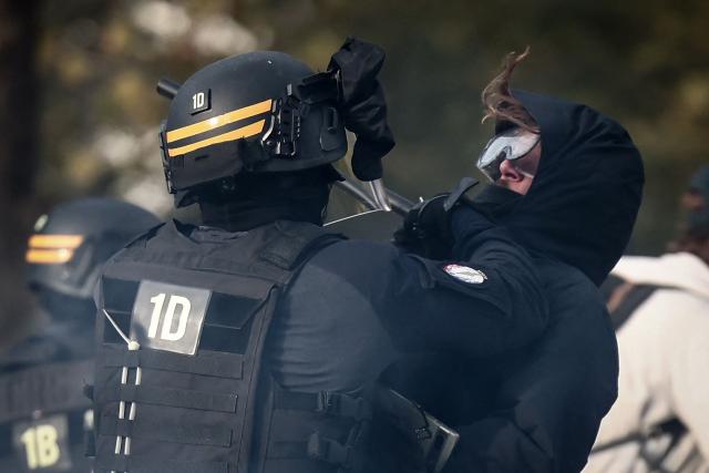 A French Republican Security Corps (CRS - Compagnies Republicaines de Securite) officer hits and pushes a protester during a demonstration in favor of purchasing power, the protection of public services, and fiscal and social justice, in Marseille, southeastern France on October 24, 2026 as part of a nationwide call for mobilisation bringing together former members of the Yellow Vest movement, labor unions, high school and university students. Protests by high school students over learning conditions sparked a movement that has since spread nationwide, fuelled by broader anger over the rising cost of living. About 70,000 security personnel will be deployed on October 24, 2026, Interior Minister said at a news conference, warning that calls for violence and looting were circulating on social media. (Photo by Thibaud MORITZ / AFP)