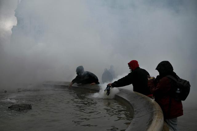 Protesters drown tear gas canisters at Place de la Bourse, in a protest ban zone, as part of a demonstration in favor of purchasing power, the protection of public services, and fiscal and social justice, in Bordeaux, western France on October 24, 2026 as part of a nationwide call for mobilisation bringing together former members of the Yellow Vest movement, labor unions, high school and university students. Protests by high school students over learning conditions sparked a movement that has since spread nationwide, fuelled by broader anger over the rising cost of living. About 70,000 security personnel will be deployed on October 24, 2026, Interior Minister said at a news conference, warning that calls for violence and looting were circulating on social media. (Photo by Philippe LOPEZ / AFP)