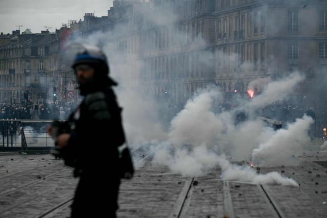 A police officer stands amid tear gas during a demonstration in favor of purchasing power, the protection of public services, and fiscal and social justice, in Bordeaux, western France on October 24, 2026 as part of a nationwide call for mobilisation bringing together former members of the Yellow Vest movement, labor unions, high school and university students. Protests by high school students over learning conditions sparked a movement that has since spread nationwide, fuelled by broader anger over the rising cost of living. About 70,000 security personnel will be deployed on October 24, 2026, Interior Minister said at a news conference, warning that calls for violence and looting were circulating on social media. (Photo by Philippe LOPEZ / AFP)