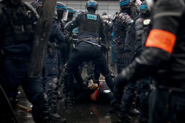 TOPSHOT - French Police officers in riot gear detain a protester during a demonstration in favor of purchasing power, the protection of public services, and fiscal and social justice, in Paris on October 24, 2026 as part of a nationwide call for mobilisation bringing together former members of the Yellow Vest movement, labor unions, high school and university students. Protests by high school students over learning conditions sparked a movement that has since spread nationwide, fuelled by broader anger over the rising cost of living. About 70,000 security personnel will be deployed on October 24, 2026, Interior Minister said at a news conference, warning that calls for violence and looting were circulating on social media. (Photo by Sameer AL-DOUMY / AFP)