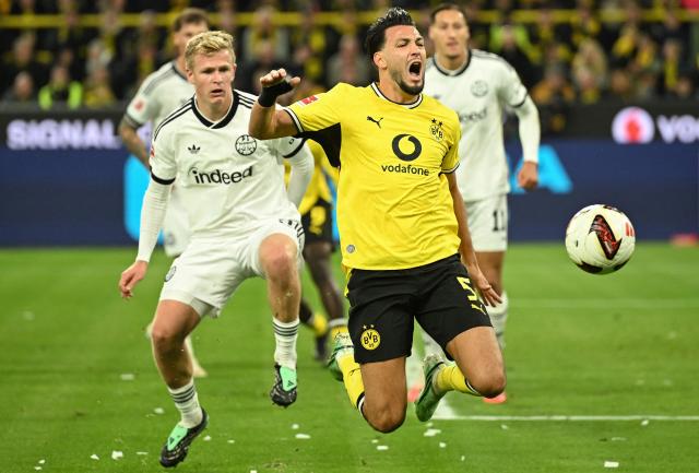 Dortmund's Algerian defender #05 Ramy Bensebaini (R) is fouled by Frankfurt's German forward #09 Jonathan Burkardt during the German first division Bundesliga football match between BVB Borussia Dortmund and Eintracht Frankfurt in Dortmund, western Germany on October 24, 2026. (Photo by INA FASSBENDER / AFP) / DFL REGULATIONS PROHIBIT ANY USE OF PHOTOGRAPHS AS IMAGE SEQUENCES AND/OR QUASI-VIDEO