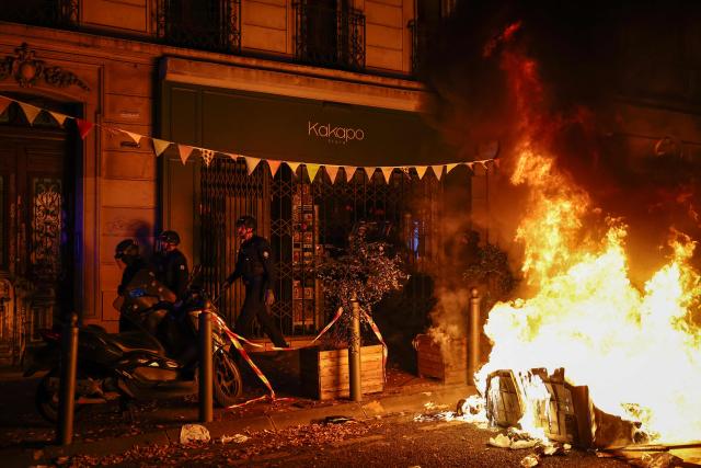 French riot police walk past a burning barricade during a demonstration in favor of purchasing power, the protection of public services, and fiscal and social justice, in Marseille, southeastern France on October 24, 2026 as part of a nationwide call for mobilisation bringing together former members of the Yellow Vest movement, labor unions, high school and university students. Protests by high school students over learning conditions sparked a movement that has since spread nationwide, fuelled by broader anger over the rising cost of living. About 70,000 security personnel will be deployed on October 24, 2026, Interior Minister said at a news conference, warning that calls for violence and looting were circulating on social media. (Photo by Thibaud MORITZ / AFP)