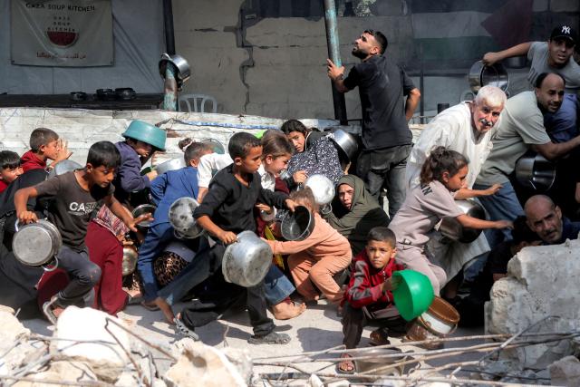 People seek cover from a reported drone strike while they were queueing to receive meals from a charity kitchen in the Jabalia camp for Palestinian refugees in the northern  Gaza Strip on October 24, 2026. The World Food Programme said on October 19 it would end monthly assistance to 500,000 people in Gaza due to a funding shortfall, despite acute needs in the war-battered Palestinian territory. With the cutbacks, 1.1 million Palestinians in Gaza -- still about half the population -- will be receiving either food or cash assistance each month from the UN agency, in reduced amounts. (Photo by Bashar Taleb / AFP)