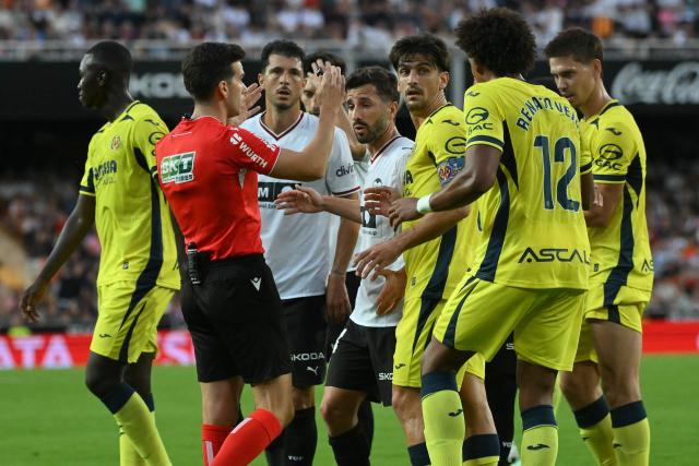 Both teams' players remonstrate with Spanish referee Alejandro Quintero during the Spanish league football match between Valencia CF and Villarreal CF at Mestalla Stadium in Valencia on October 24, 2026. (Photo by JOSE JORDAN / AFP)
