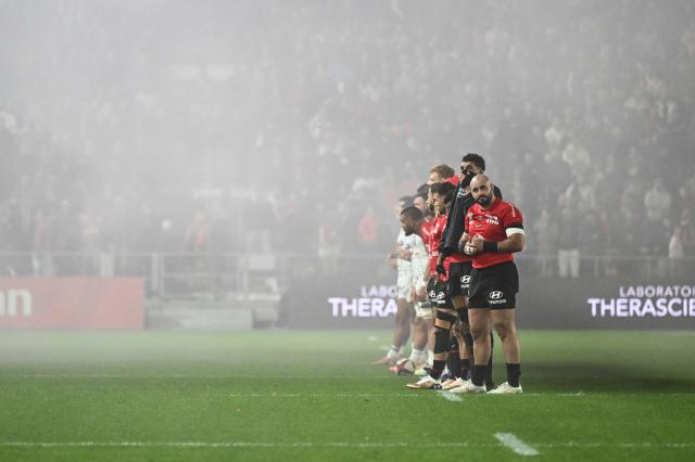 Pau's players and Toulon’s player's stand in smoke ahead of the French Top14 rugby union match between RC Toulon and Section Paloise (Pau) at the Stade Mayol in Toulon, southeastern France, on October 24, 2026. (Photo by Justine Meddah / AFP)