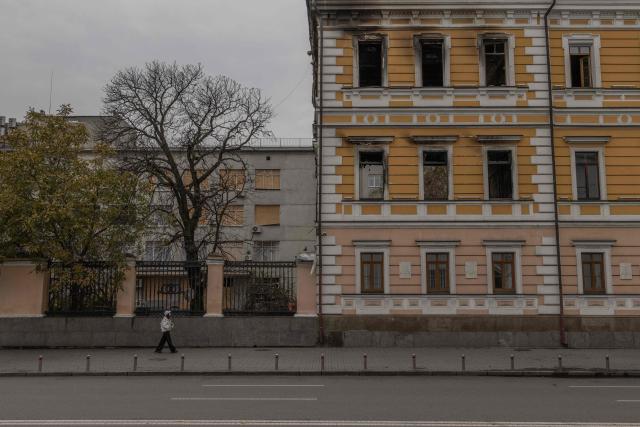 A woman walks past the Ukrainian National Academy of Sciences building, which was damaged in a Russian air attack, in downtown Kyiv on October 24, 2026, amid the Russian invasion of Ukraine. (Photo by Roman PILIPEY / AFP)