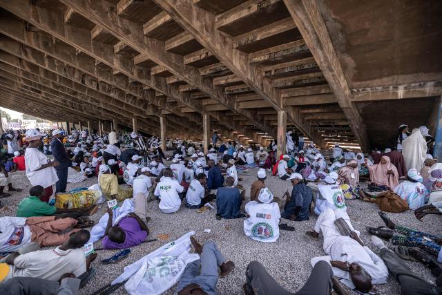 Supporters of All Progressives Congress (APC) shelter from the sun under the stands during a presidential campaign flag-off rally at the Ranchers Bess stadium in Kaduna, on October 24, 2026. Nigerian President Bola Tinubu launches his re-election campaign on Saturday facing voter anger over insecurity and economic hardships. (Photo by Light Oriye Tamunotonye / AFP)