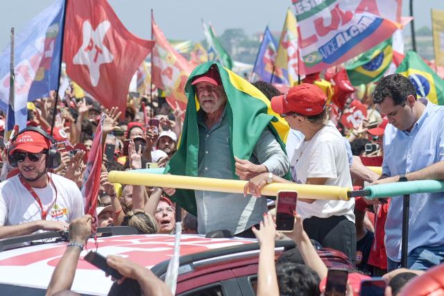 Brazil's President and presidential candidate Luiz Inacio Lula da Silva covers himself from the sun with a Brazilian flag during a campaign rally at Copacabana beach in Rio de Janeiro, Brazil on October 24, 2026, ahead of the presidential election runoff. (Photo by TERCIO TEIXEIRA / AFP)