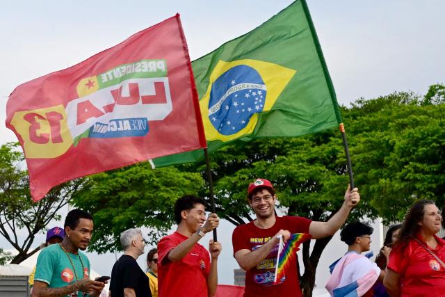 Supporters of Brazil's President and presidential candidate Luiz Inacio Lula da Silva wave to passing cars in Brasilia on October 24, 2026, ahead of the presidential election runoff. (Photo by Pablo PORCIUNCULA / AFP)
