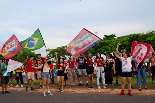 Supporters of Brazil's President and presidential candidate Luiz Inacio Lula da Silva wave to passing cars in Brasilia on October 24, 2026, ahead of the presidential election runoff. (Photo by Pablo PORCIUNCULA / AFP)