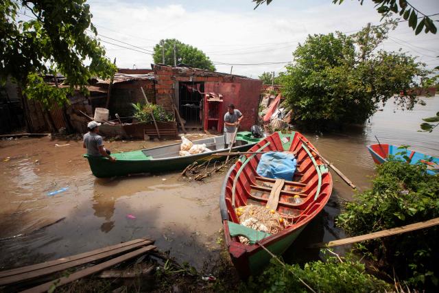 Men are transported by canoe through flooded streets after the overflow of the Parana river, following heavy rainfall and the opening of the floodgates at the Yacyreta hydroelectric dam, in Corrientes, Argentina on October 24, 2026. More than 2,000 people have been forced to leave their homes due to flooding linked to the El Nino climate phenomenon affecting northeastern Argentina. The emergency caused two deaths last weekend and is expected to persist for the coming months. Heavy rainfall in recent weeks has dangerously increased water levels in the Iguazu, Parana, and Uruguay rivers, which run along northeastern Argentina, forming natural borders with Brazil, Paraguay, and Uruguay before flowing into the Rio de la Plata. (Photo by Joaquin Meabe / AFP)