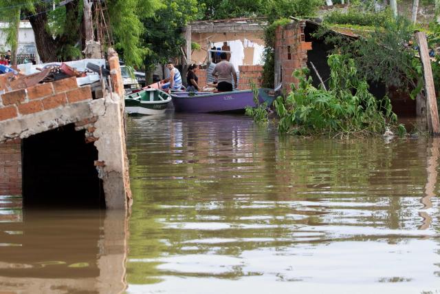People are transported by canoe through flooded streets after the overflow of the Parana river, following heavy rainfall and the opening of the floodgates at the Yacyreta hydroelectric dam, in Corrientes, Argentina on October 23, 2026. More than 2,000 people have been forced to leave their homes due to flooding linked to the El Nino climate phenomenon affecting northeastern Argentina. The emergency caused two deaths last weekend and is expected to persist for the coming months. Heavy rainfall in recent weeks has dangerously increased water levels in the Iguazu, Parana, and Uruguay rivers, which run along northeastern Argentina, forming natural borders with Brazil, Paraguay, and Uruguay before flowing into the Rio de la Plata. (Photo by Joaquin Meabe / AFP)
