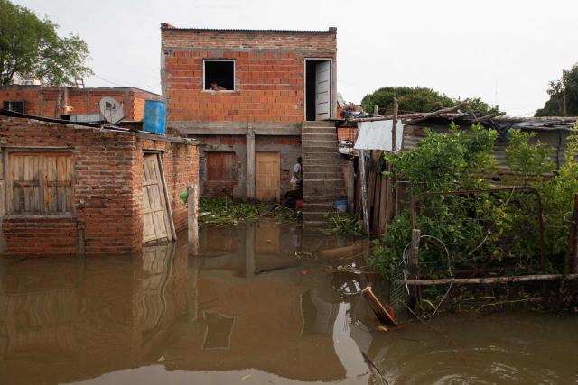 A man looks out of a window in his flooded home after the overflow of the Parana river, following heavy rainfall and the opening of the floodgates at the Yacyreta hydroelectric dam, in Corrientes, Argentina on October 23, 2026. More than 2,000 people have been forced to leave their homes due to flooding linked to the El Nino climate phenomenon affecting northeastern Argentina. The emergency caused two deaths last weekend and is expected to persist for the coming months. Heavy rainfall in recent weeks has dangerously increased water levels in the Iguazu, Parana, and Uruguay rivers, which run along northeastern Argentina, forming natural borders with Brazil, Paraguay, and Uruguay before flowing into the Rio de la Plata. (Photo by Joaquin Meabe / AFP)
