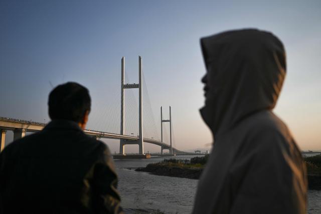 People look on in Dandong, in northeastern China's Liaoning province, next to the new cross-border bridge linking China and North Korea at sunrise on October 25, 2026. North Korean leader Kim Jong Un returned home October 24 after a day-long trip to the Chinese border city of Dandong, Beijing's state media reported, though the purpose of the unannounced visit was not immediately clear. (Photo by Pedro PARDO / AFP)