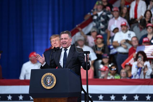 US President Donald Trump looks on as CEO of Audi AG Gernot Dollner speaks at a midterm election campaign rally at Guardian Centers of Georgia in Perry, Georgia on October 24, 2026. President Trump is traveling around the country to try to give a boost to Republicans in tight midterm races. (Photo by Brendan SMIALOWSKI / AFP)