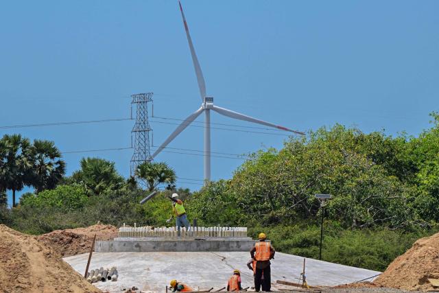 This photograph taken on October 2, 2026 shows workers installing wind turbine components for a wind power project in Sri Lanka's Mannar Peninsula. The government aims to generate 70 percent of the country's electricity from renewable sources by 2030, including wind power. But it has frozen new projects in Mannar to ease local opposition. Since they appeared six years ago, the Mannar wind turbines have been blamed for a host of problems -- from dwindling catches to floods, fuelling opposition to green energy projects as fuel costs soar. (Photo by Ishara S. KODIKARA / AFP)