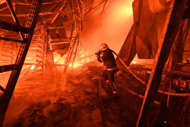 A Ukrainian firefighter extinguishes a blaze at Epicentr hypermarket that was damaged following a Russian air attack, in Kharkiv, late on October 24, 2026, amid the Russian invasion of Ukraine. (Photo by SERGEY BOBOK / AFP)