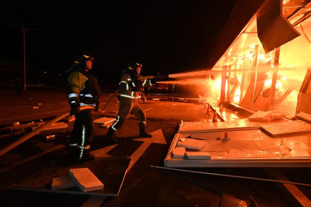 Ukrainian firefighters extinguish a blaze at Epicentr hypermarket that was damaged following a Russian air attack, in Kharkiv, late on October 24, 2026, amid the Russian invasion of Ukraine. (Photo by SERGEY BOBOK / AFP)