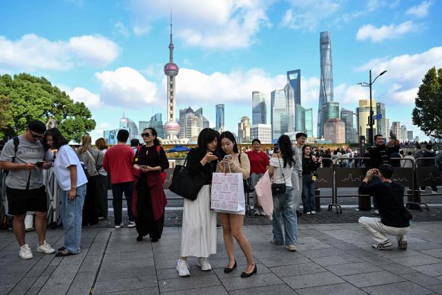 People visit The Bund promenade in Shanghai on October 25, 2026. (Photo by Hector RETAMAL / AFP)