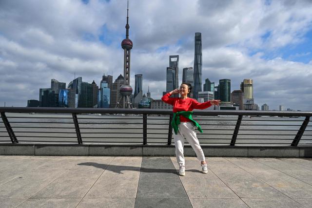 A woman dances on The Bund promenade along the Huangpu river in Shanghai on October 25, 2026. (Photo by Hector RETAMAL / AFP)