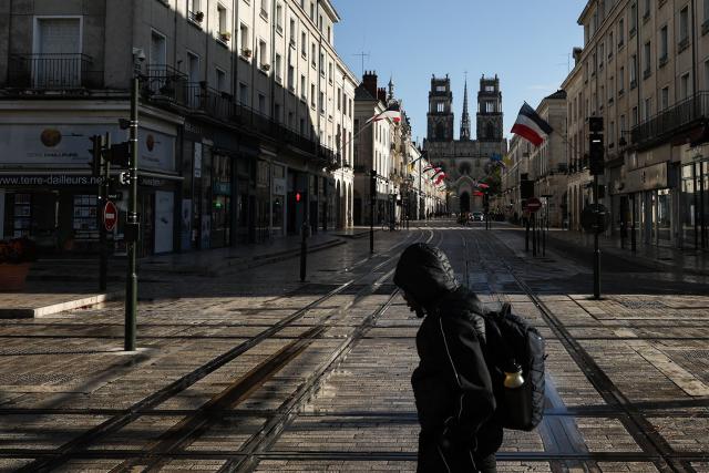 A pedestrian walks over an empty street and tramway lines with a view of a Cathedral in  the background ahead of a demonstration "against racism, fascism and imperialism" on the sidelines of the Congress of the Far-right party Rassemblement National (RN) in Orleans, central France on October 25, 2026. On October 25, 2026, gatherings will remain banned in a large part of the Orléans urban area. But several organizations may call for people to assemble outside the prohibited zone, as the day after a congress in Orléans that passed without any major incident but under heavy police surveillance, a French far right candidate is due to deliver her first major campaign speech in the afternoon. (Photo by SIMON WOHLFAHRT / AFP)