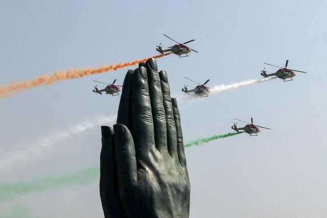 Indian Air Force (IAF) Sarang helicopters fly in a formation with tricolour trails during the 'Wings Over Ganges' air show over the river Ganges, at Namo Ghat in Varanasi on October 25, 2026. (Photo by Niharika KULKARNI / AFP)