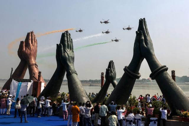 Indian Air Force (IAF) Sarang helicopters fly in a formation with tricolour trails during the 'Wings Over Ganges' air show over the river Ganges, at Namo Ghat in Varanasi on October 25, 2026. (Photo by Niharika KULKARNI / AFP)