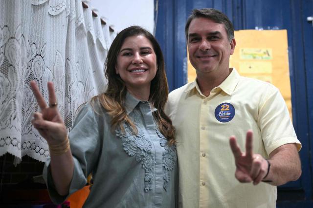 Brazil's right-wing senator and Liberal Party (PL) presidential candidate Flavio Bolsonaro and his wife Fernanda Bolsonaro make V-for-victory signs during the presidential runoff election at a polling station in Rio de Janeiro, Brazil, on October 25, 2026. Flavio Bolsonaro faces President Luiz Inacio Lula da Silva in a runoff that will determine whether Brazil remains one of the few leftist nations in the region or joins a regional swing to the right championed by his ally, US President Donald Trump. (Photo by MAURO PIMENTEL / AFP)